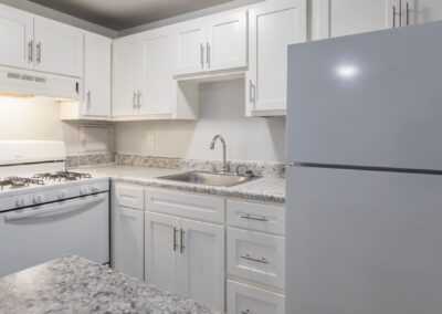 A modern kitchen featuring white cabinets and elegant granite countertops, showcasing a clean and bright aesthetic